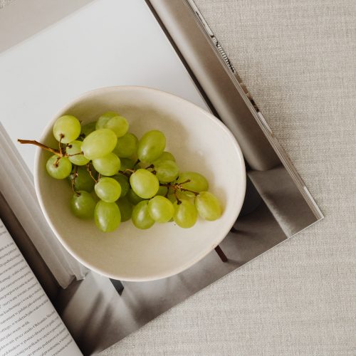kaboompics_Magazine and grapes in a bowl on a linen couch